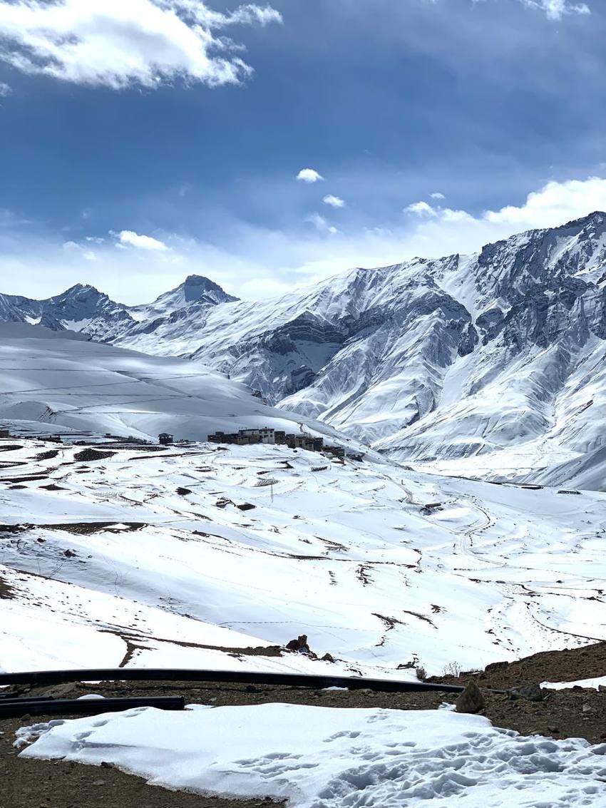 A village on a snow-covered plateau beneath Himalayan peaks