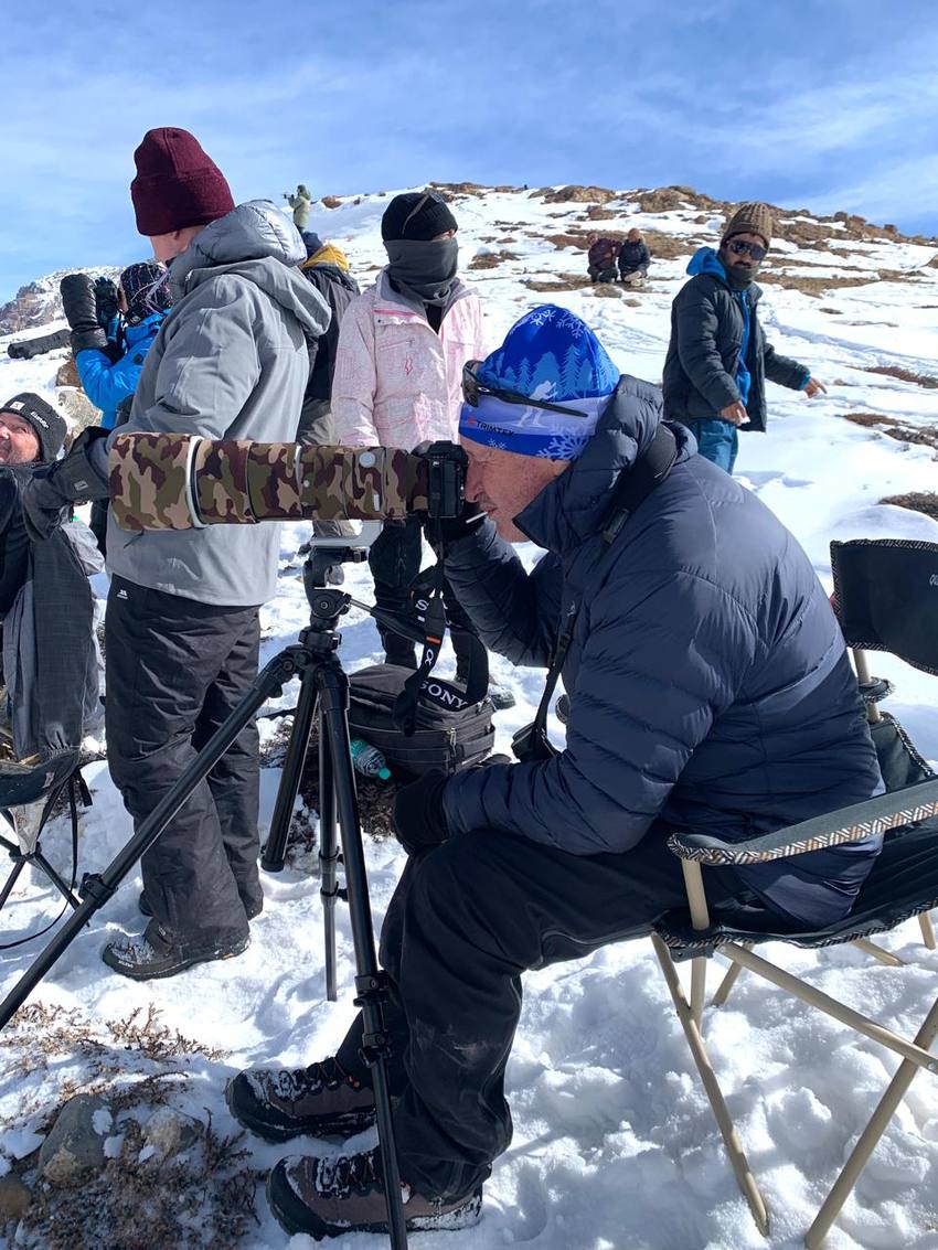 A photographer behind a long lens on a tripod, the group watching the slopes